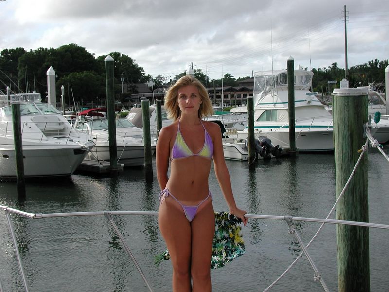 Ухоженная светловолосая девушка развлекается без одежды на палубе яхты